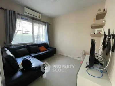 Cozy living room with black leather sofa and wall-mounted TV, perfect for relaxation.