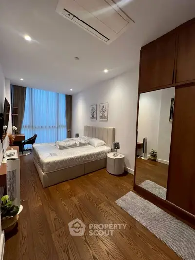 Spacious modern bedroom with wooden flooring and stylish decor