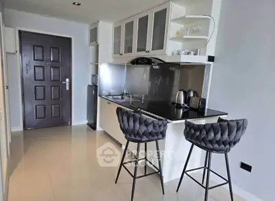 Modern kitchen with sleek black countertops and stylish bar stools in a contemporary apartment.