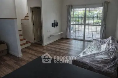 Spacious living room with large window and staircase, perfect for modern living.