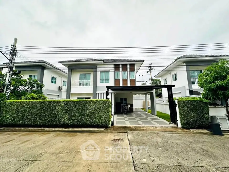 Modern two-story house with driveway and lush greenery in a serene neighborhood.