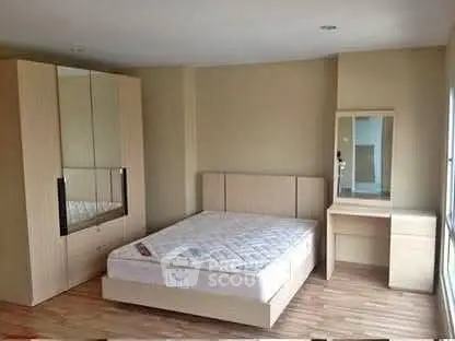 Spacious bedroom with modern wooden furniture and ample natural light.