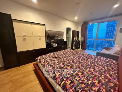 Spacious bedroom with city view and modern furnishings in high-rise apartment.