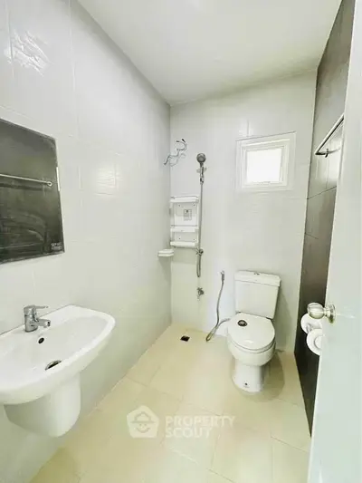 Compact modern bathroom with white tiles and essential fixtures.