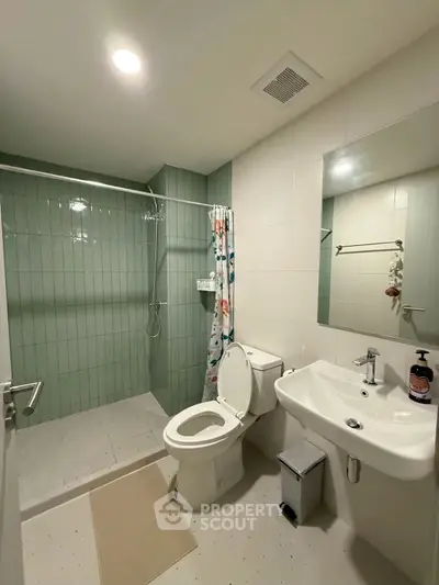 Modern bathroom with shower, toilet, and sink in sleek design.