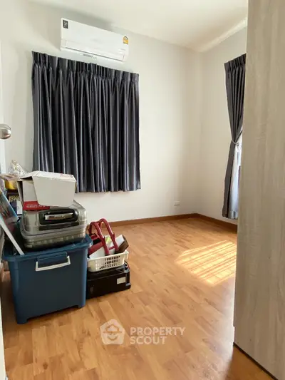Cozy room with wooden flooring and air conditioning, ideal for storage or small office setup.