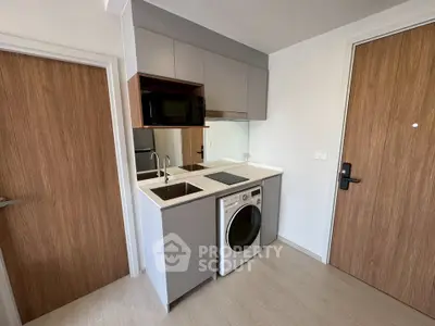 Modern compact kitchen with integrated appliances and sleek cabinetry in a stylish apartment.