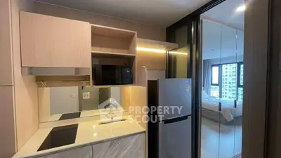 Modern compact kitchen with sleek appliances and open view to bedroom