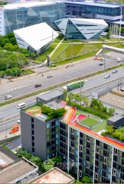 Aerial view of modern building with colorful rooftop and unique architecture in urban setting.