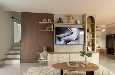 Modern living room with stylish decor and built-in shelving, featuring a sleek TV and cozy ambiance.