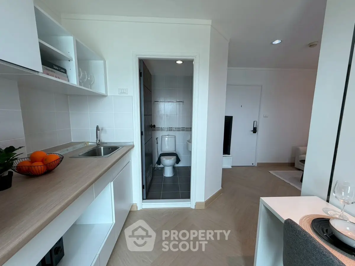 Modern studio apartment with compact kitchen and bathroom, featuring sleek design and efficient use of space.