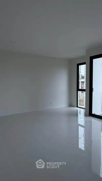 Spacious modern living room with large windows and glossy tiled floor, perfect for natural light lovers.