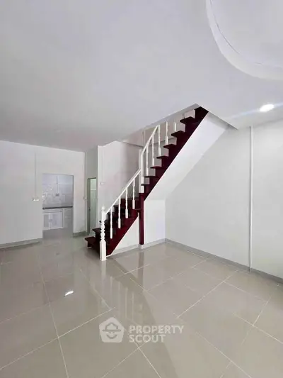 Spacious modern interior with elegant staircase and glossy tiled flooring, perfect for stylish living.