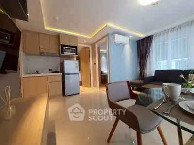 Modern open-layout living room with kitchen, featuring sleek furniture and natural light.