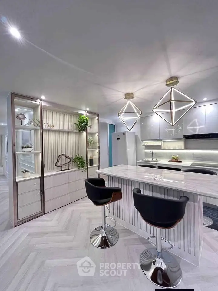 Modern kitchen with sleek design, featuring stylish bar stools and geometric pendant lights.