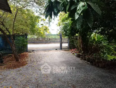 Charming garden entrance with lush greenery and secure gate access.