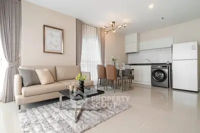 Modern open-plan living room with kitchen, featuring sleek furniture and appliances.