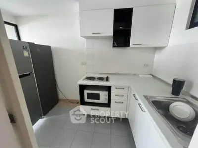 Modern kitchen with sleek white cabinets and appliances, featuring a compact layout and efficient design.