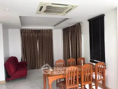 Spacious dining area with elegant wooden table and chairs, featuring modern ceiling air conditioning.