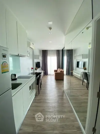 Modern open-layout apartment with sleek kitchen and cozy living area, featuring large windows and stylish decor.