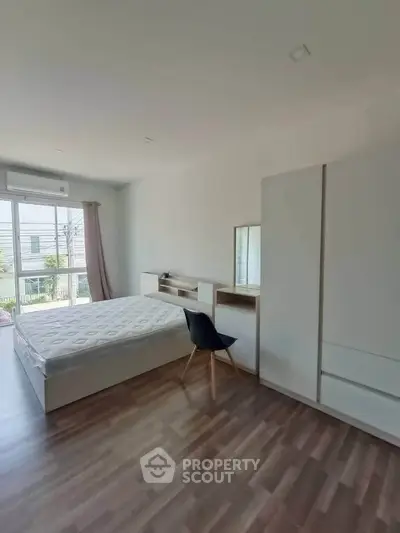 Spacious bedroom with modern furniture and large window for natural light