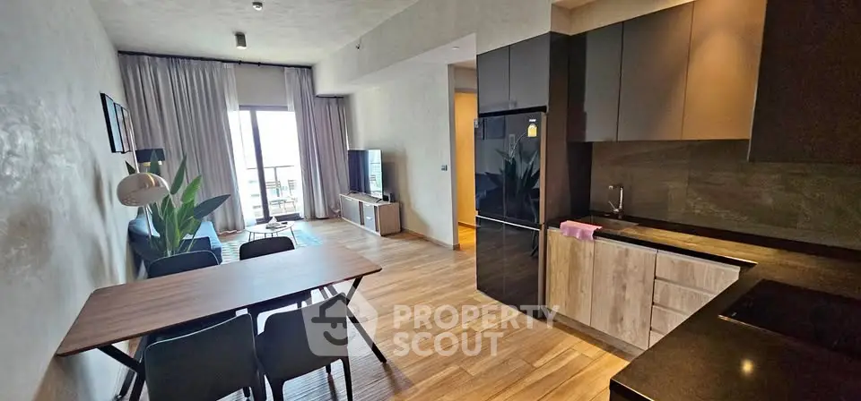 Modern open-plan living room and kitchen with stylish decor and balcony view.