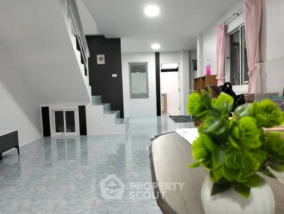 Spacious modern living room with staircase and large windows, perfect for family gatherings.