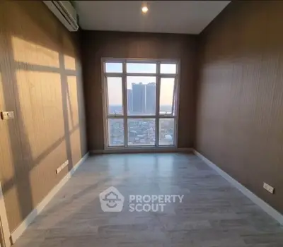 Spacious room with large window offering stunning city view and ample natural light.