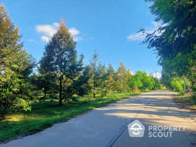 Scenic view of lush green garden with paved pathway under clear blue sky