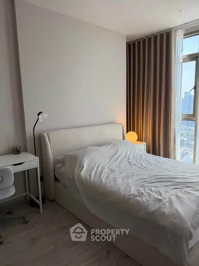 Modern bedroom with city view, featuring a cozy bed, desk, and stylish lighting.