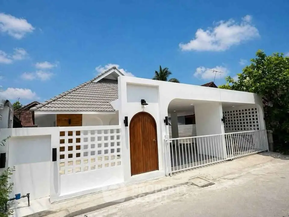 Charming modern house with white facade and wooden accents under a clear blue sky.