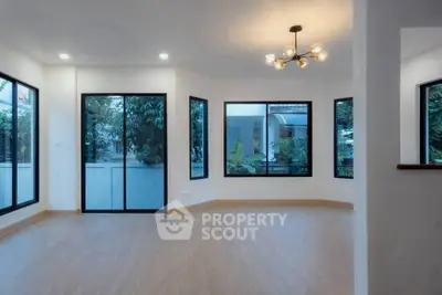 Spacious modern living room with large windows and stylish lighting, offering a bright and airy atmosphere.