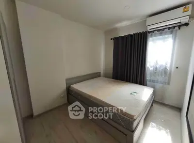 Spacious bedroom with natural light and modern air conditioning unit.
