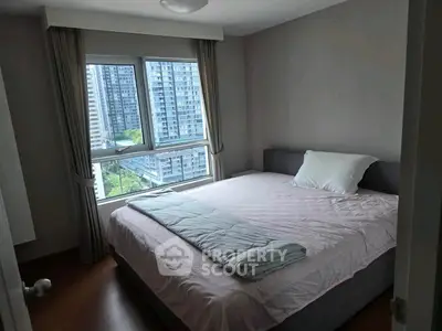 Modern bedroom with large window offering city view in high-rise apartment