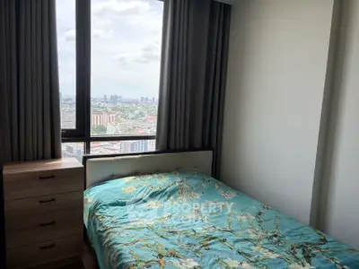Cozy bedroom with stunning city view from large window, featuring elegant decor and ample natural light.