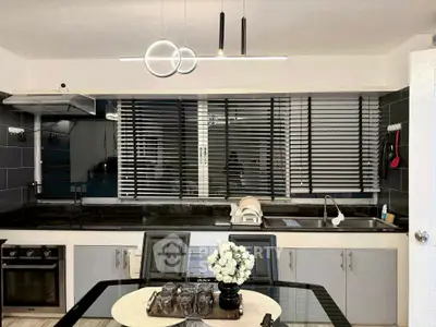 Modern kitchen with sleek black countertops and stylish lighting fixtures.