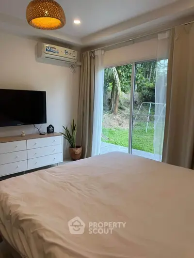 Cozy bedroom with garden view, featuring a large window, air conditioning, and modern decor.