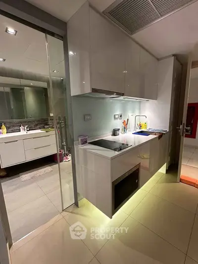 Modern kitchen with sleek cabinetry and under-cabinet lighting adjacent to a stylish bathroom.