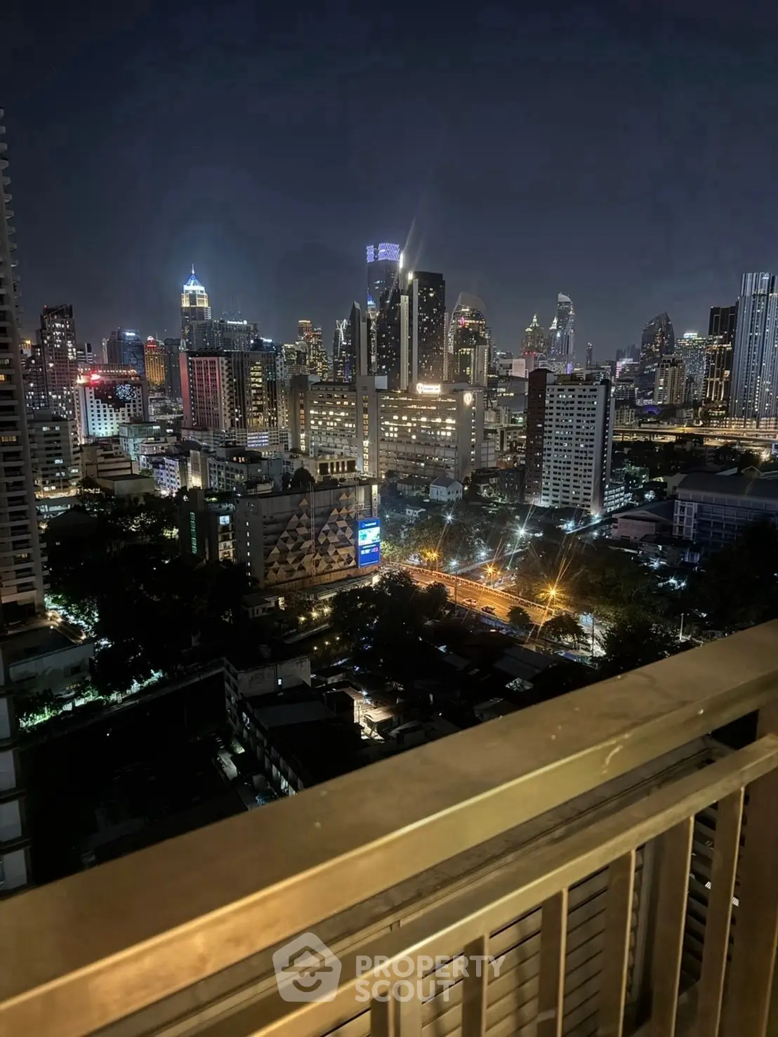 Stunning city skyline view from a high-rise balcony at night, showcasing vibrant urban lights.