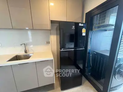 Modern kitchen with sleek cabinetry and black refrigerator in a compact layout.