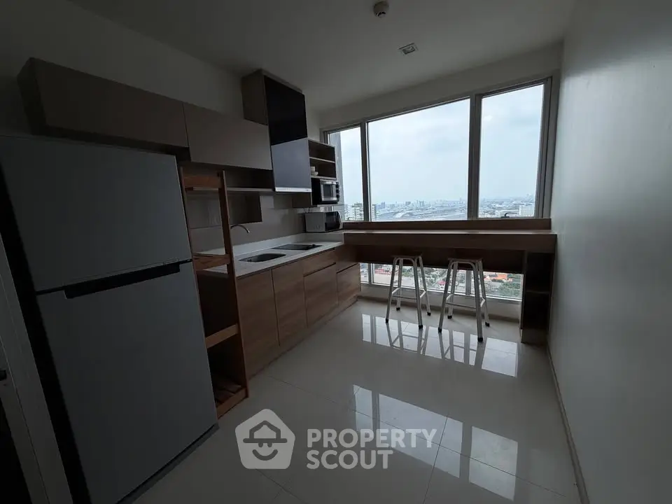 Modern kitchen with city view, featuring sleek cabinetry and bar seating by large windows.