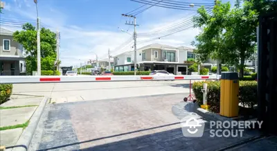 Gated community entrance with modern houses and lush greenery