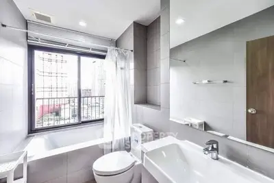 Modern bathroom with city view, featuring sleek fixtures and a large window.