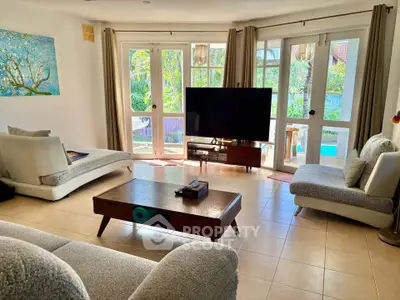 Spacious living room with modern furniture and pool view, perfect for relaxation and entertainment.