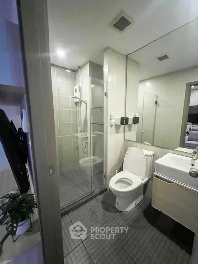 Modern bathroom with glass shower and sleek fixtures in contemporary apartment.