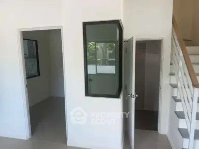 Modern interior with staircase and multiple rooms, featuring sleek design and natural light.