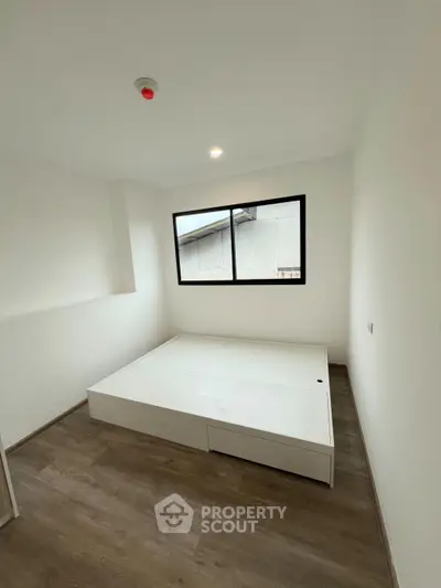 Minimalist bedroom with wooden flooring and large window for natural light