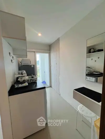 Modern kitchen with sleek black countertops and appliances, featuring a bright open layout and balcony access.