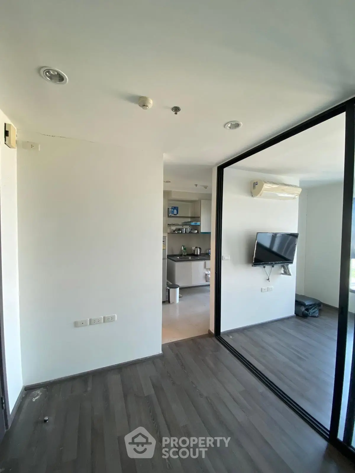 Modern apartment interior with sleek design and open layout, featuring a wall-mounted TV and stylish flooring.