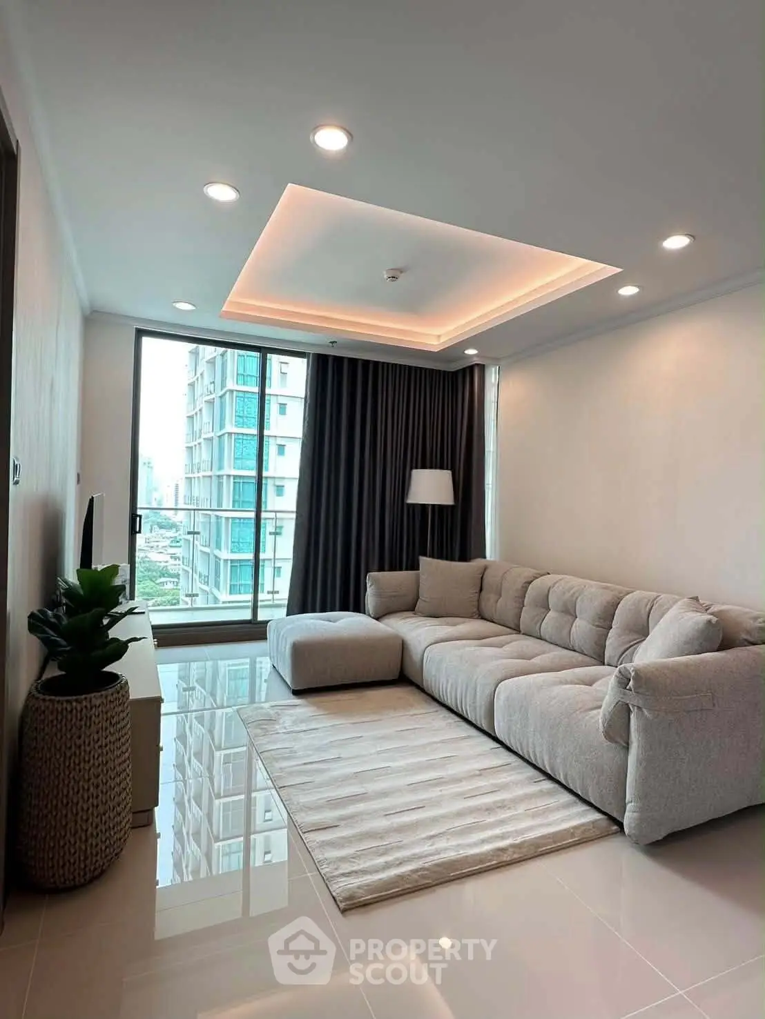 Modern living room with plush sofa and city view, featuring elegant lighting and sleek flooring.